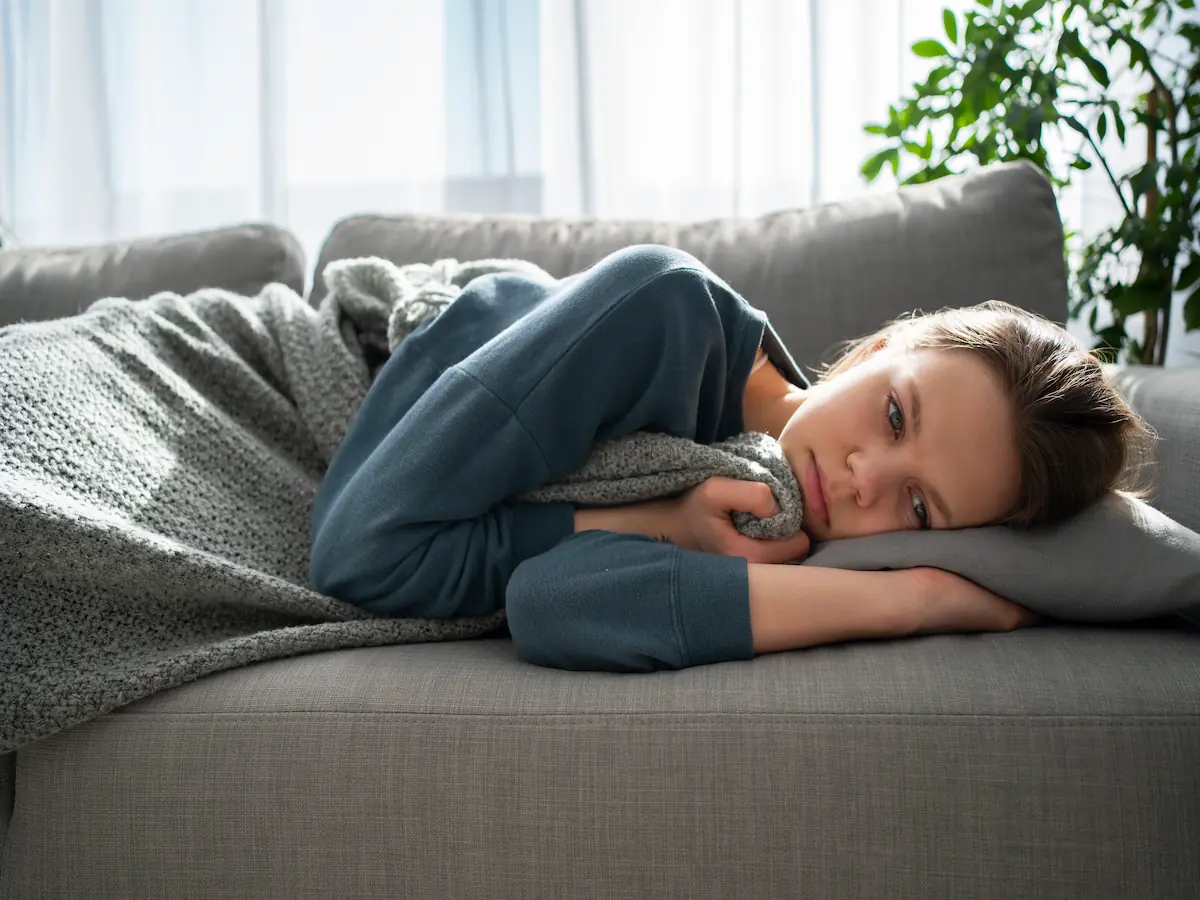 Jeune femme allongée sur un canapé, regard vide, illustrant la fatigue profonde et persistante liée à l'hyperthyroïdie