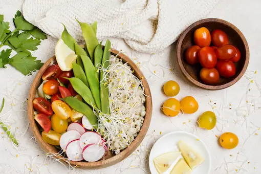 Bol en bois garni de légumes colorés, pois gourmands et radis, illustrant l'alimentation en naturopathie