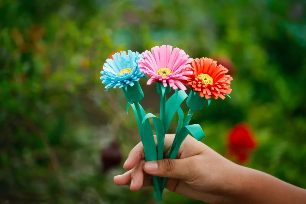Mains créant des fleurs en origami pour améliorer la concentration et la sérénité par l'art du papier.