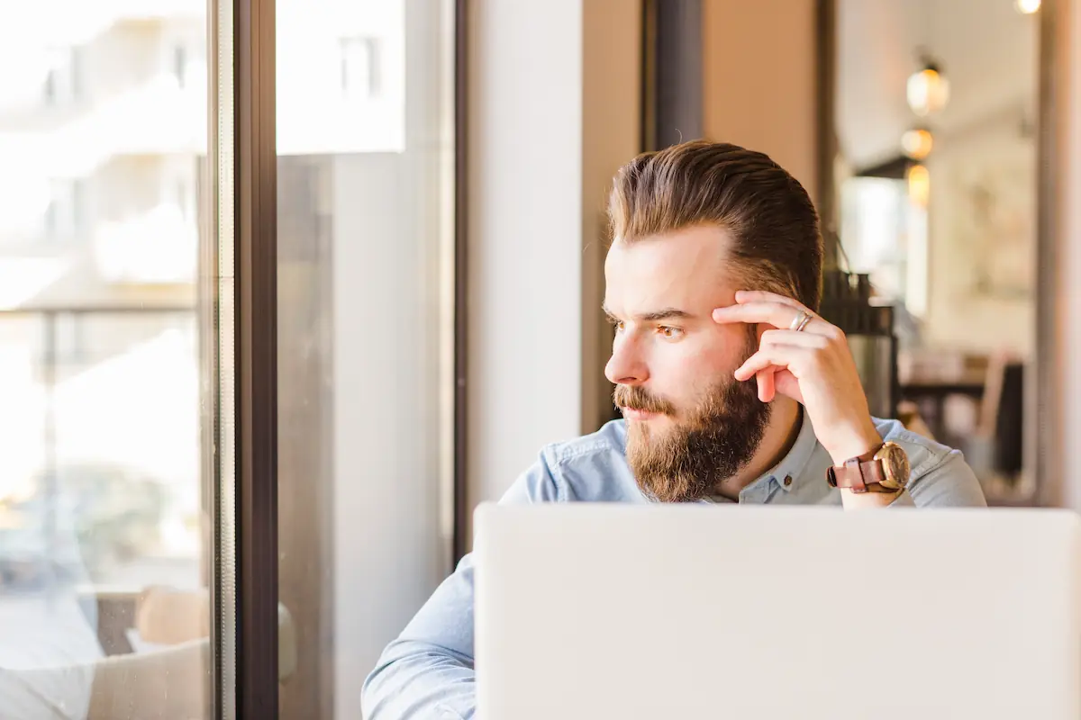 Homme au regard absent devant son ordinateur dans un café, illustrant la perte de concentration au travail