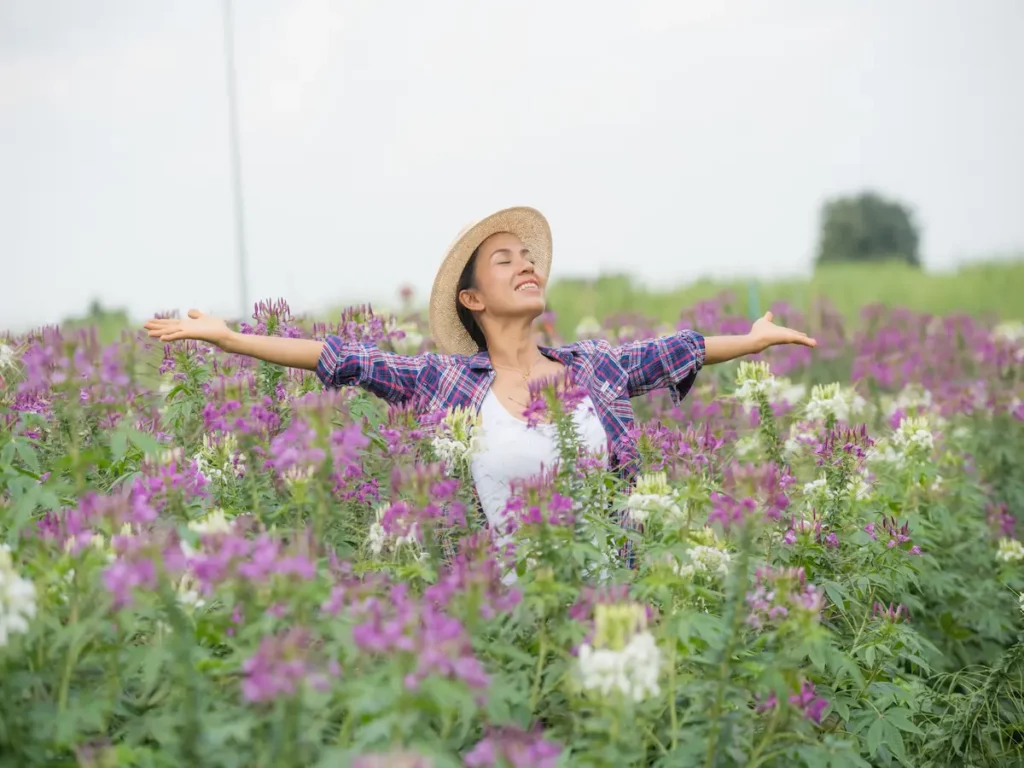 Bien-être au printemps : femme souriante dans un champ de fleurs, symbole de détox naturopathie sans excès