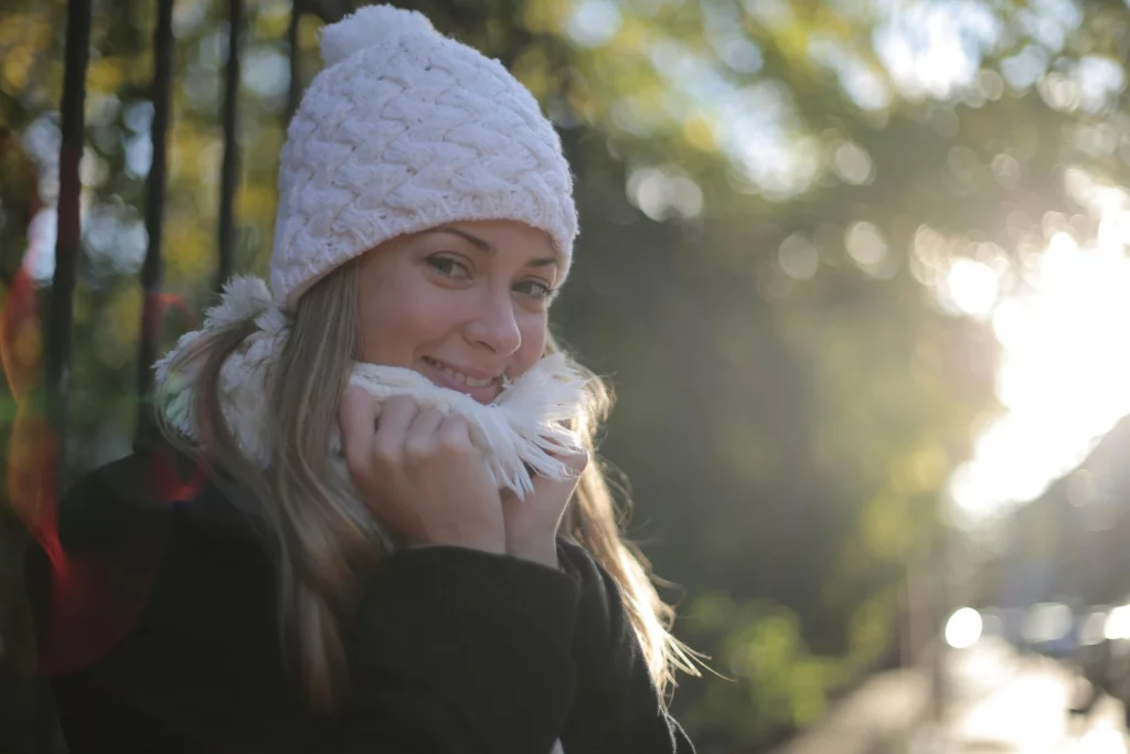 Femme souriante bien au chaud en hiver pour illustrer la saisonnalité et le cocooning en naturopathie