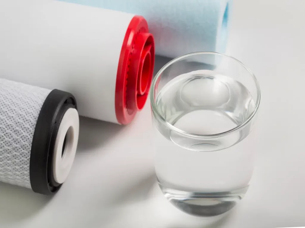 Filtres à eau et verre d’eau sur fond blanc, pour illustrer la filtration selon votre objectif et votre eau.