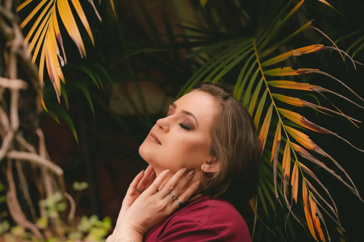 Femme de profil les yeux fermés, main posée à la base du cou au niveau de la thyroïde, ambiance apaisée — traitement naturel hypothyroïdie
