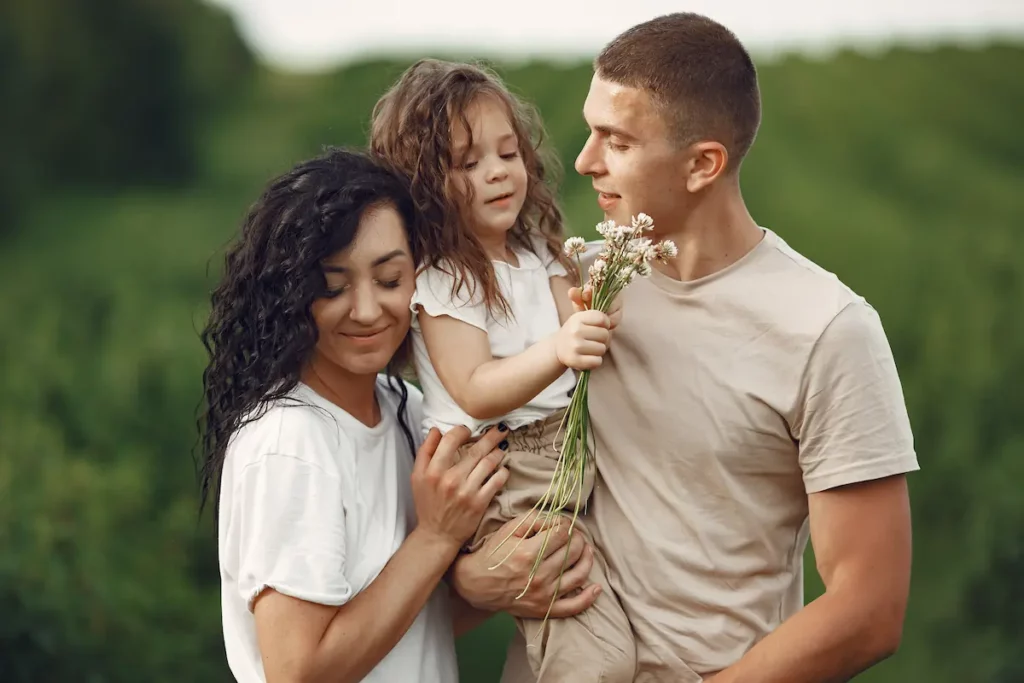 Parents et petite fille dans un champ ensoleillé, moment calme en famille pour apaiser le foyer.
