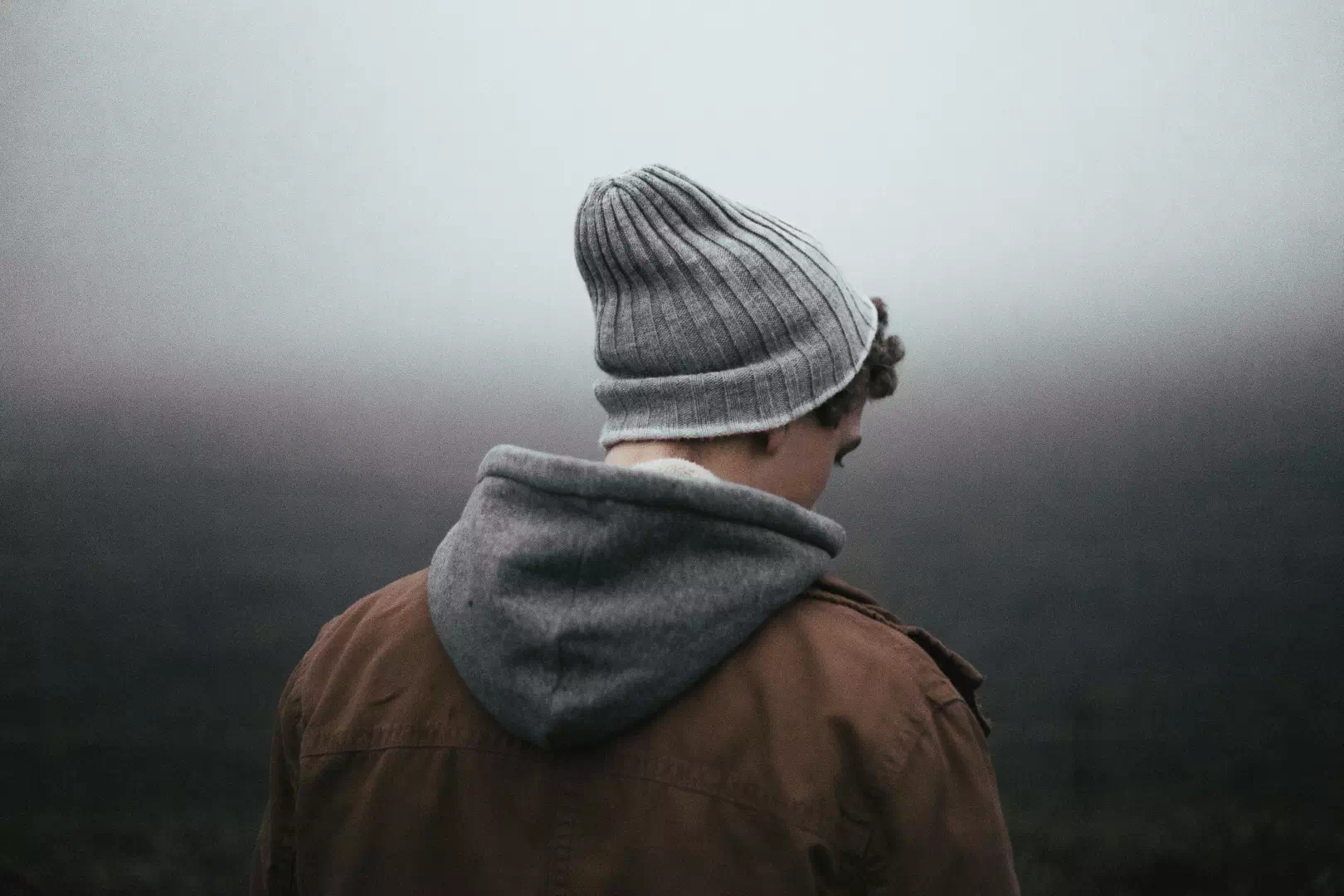 Homme de dos dans le brouillard symbolisant le manque de motivation en hiver et la fatigue liée au manque de lumière naturelle.