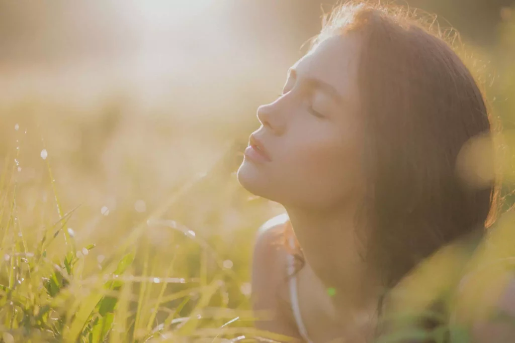 Jeune femme sereine allongée dans l'herbe évoquant la prévention et les solutions naturelles proposées par la naturopathie contre les infections urinaires.