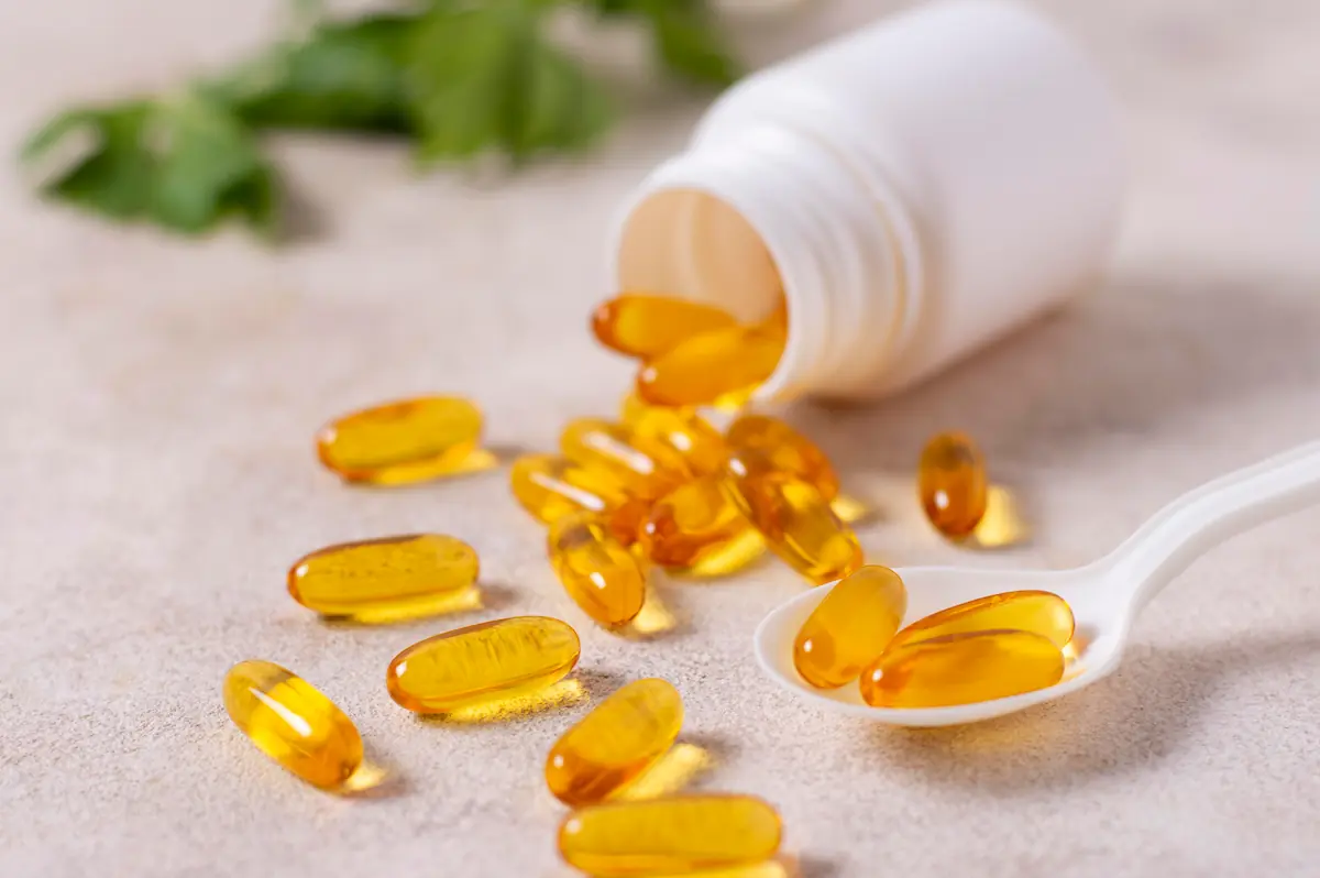 Gélules d’oméga 3 dorées près d’un flacon ouvert, pour illustrer choix et dosage utile