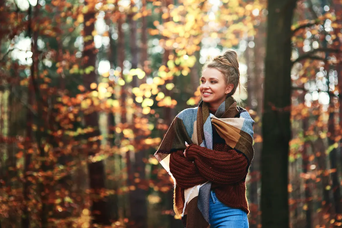 Jeune femme en promenade dans une forêt d'automne, la marche régulière soutient la circulation et les émonctoires.