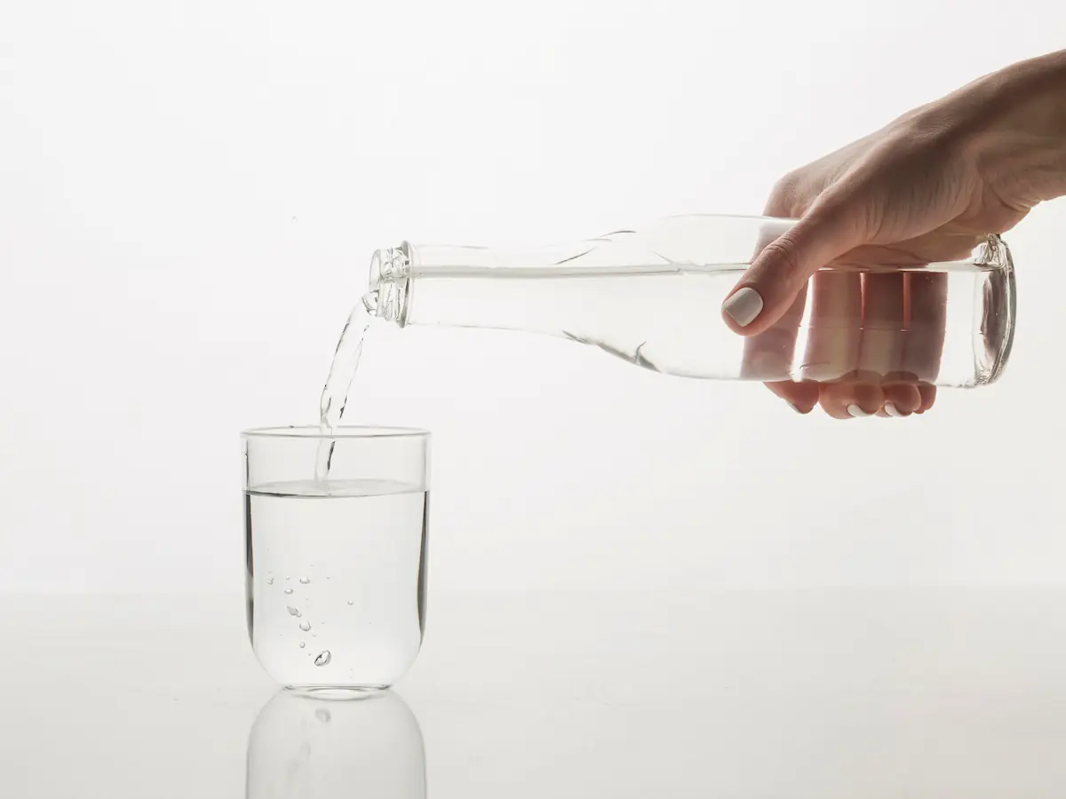 Personne versant de l’eau dans un verre, repère pour choisir entre robinet, filtration ou bouteille.