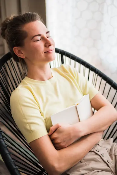 Femme détendue, yeux fermés, sourire apaisé, illustrant les bienfaits de la réflexologie plantaire sur l'état de bien-être