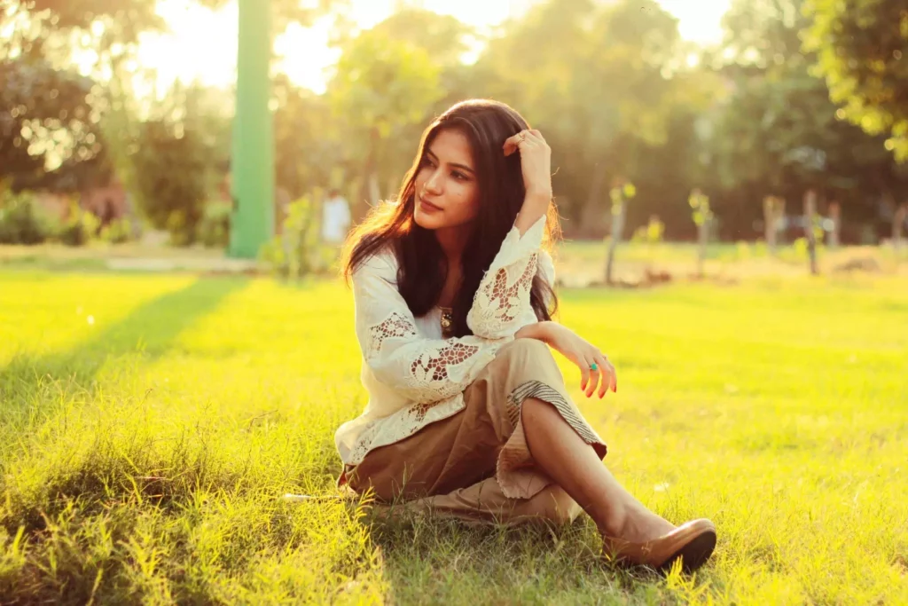 Femme sereine assise dans l'herbe illustrant une solution naturelle au stress chronique pour retrouver son équilibre intérieur.